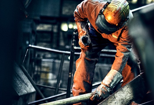 Production specialist wearing safety clothes is holding a copper tube