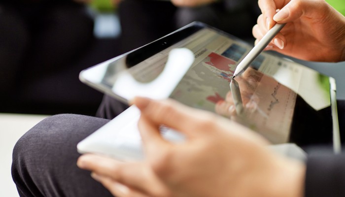 Two female hands holding a tablet and a touchpen