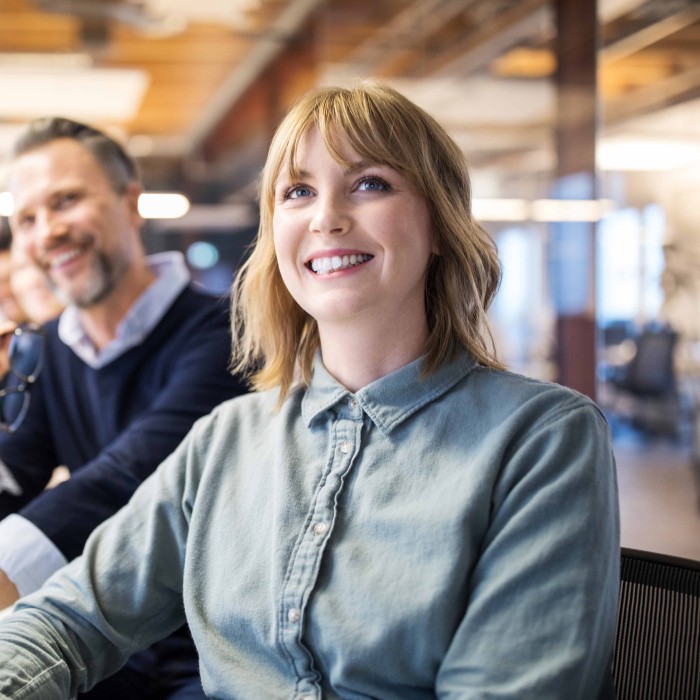 Young and smiling female employee with her co-workers