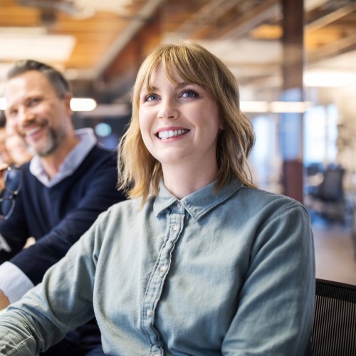 Young and smiling female employee with her co-workers