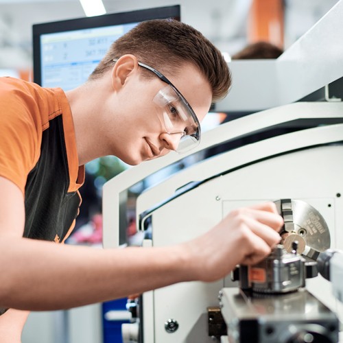 Young male trainee working on machine