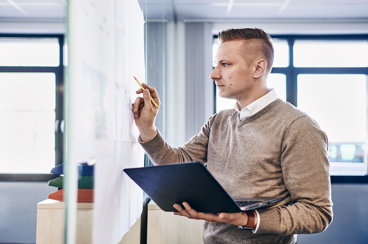 Engineer holding a folder while writing on a whiteboard