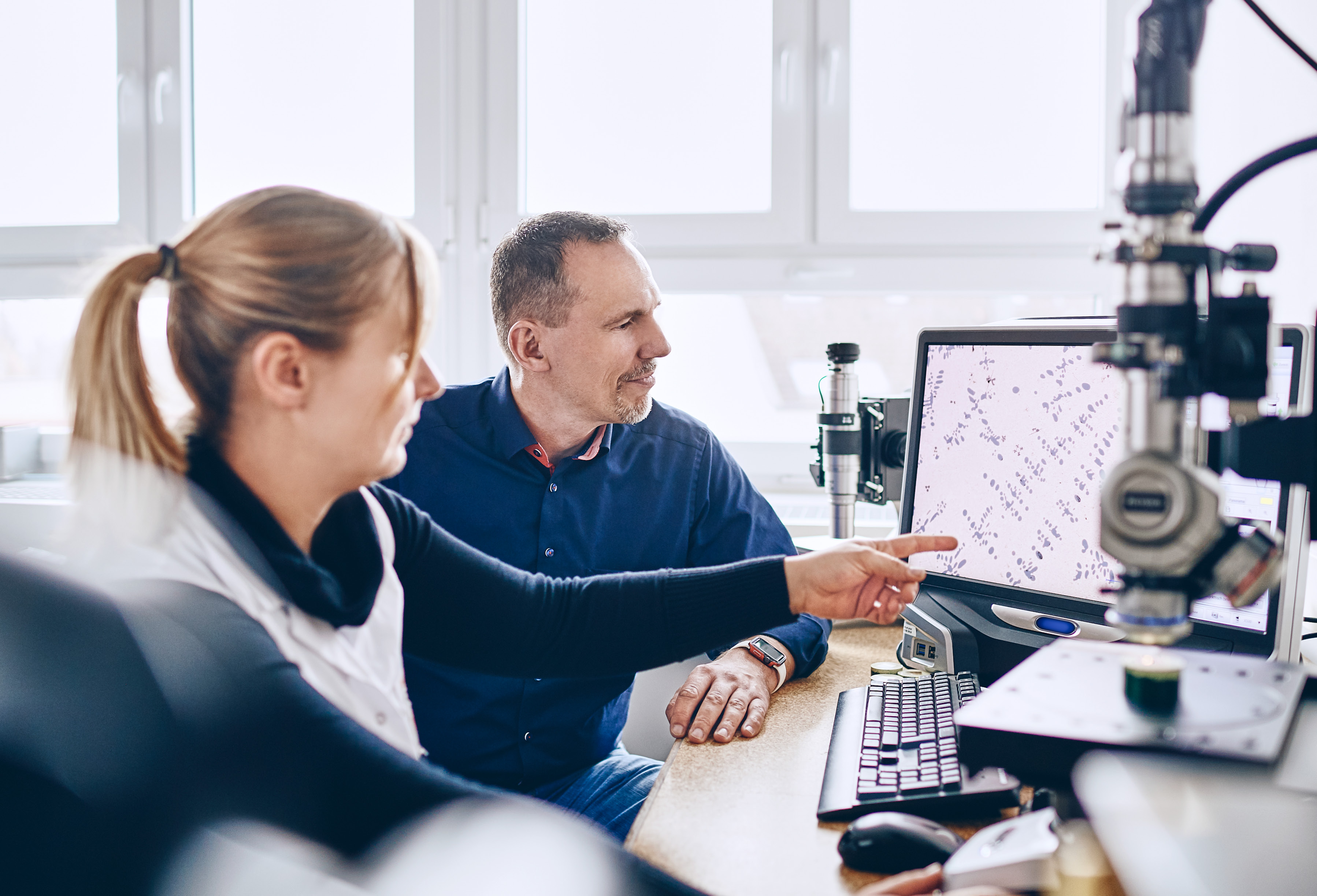 Two material scientists sitting together in front of a electron microscope