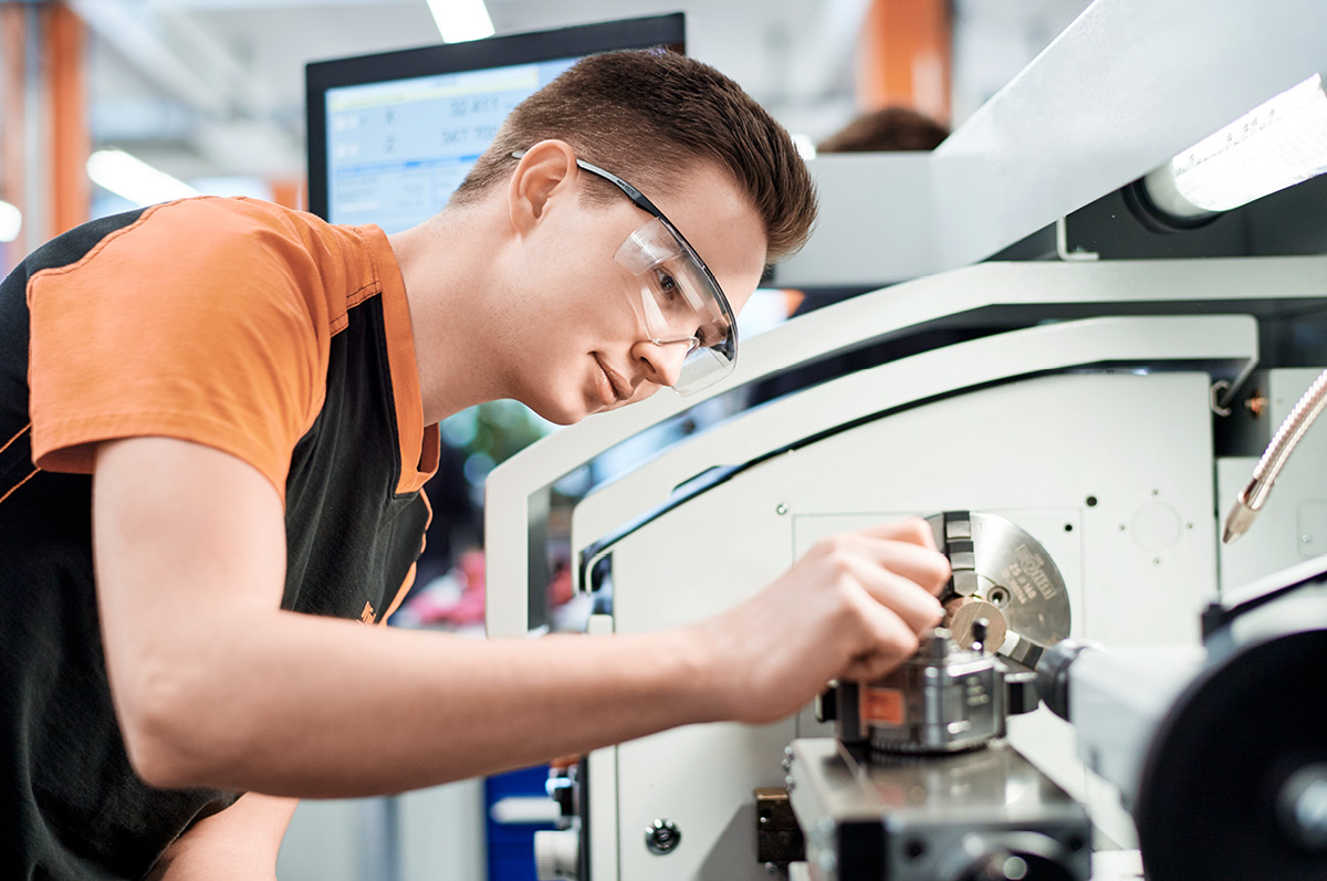 Young male trainee working on machine