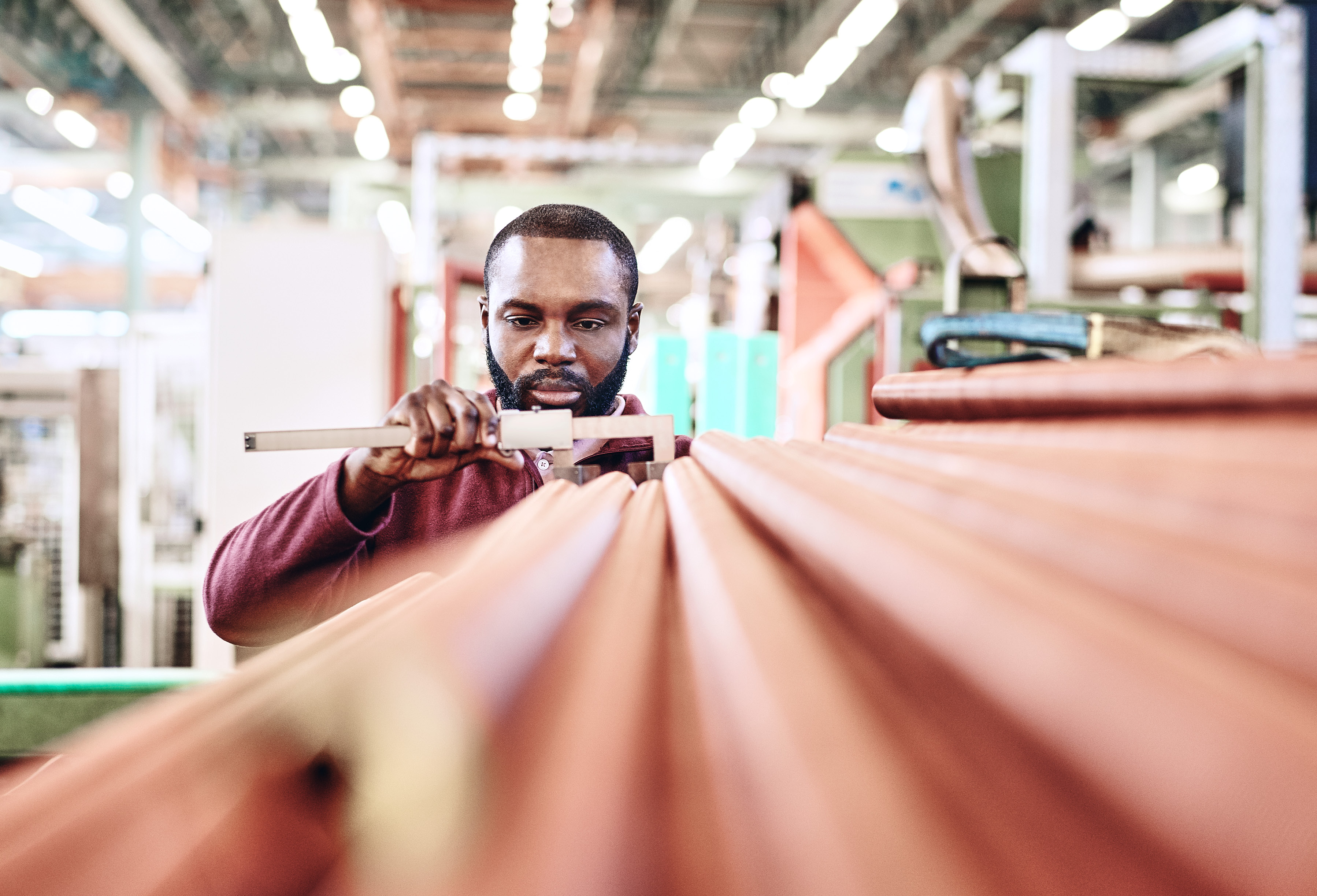 Production specialist measuring copper tubes with a caliper