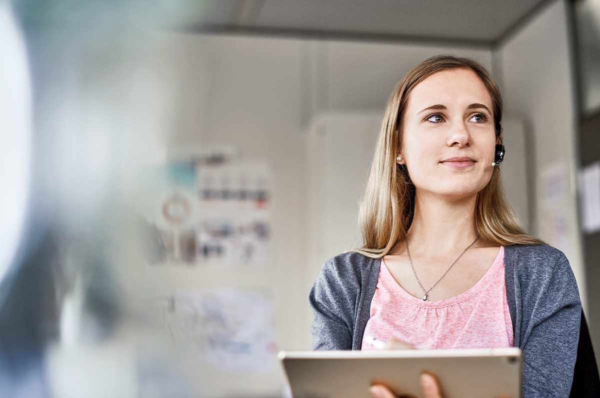 Young and smiling female employee wearing a headset